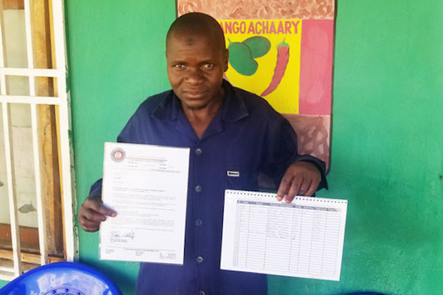 A chili processor in Malawi displays his certificate and income book