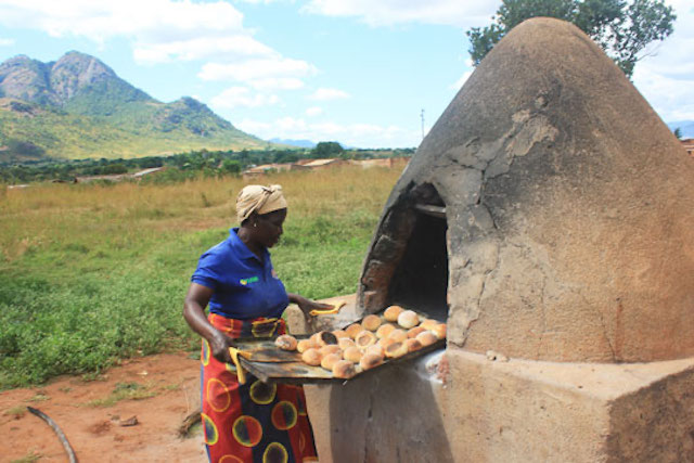A woman in Mozambique bakes soy rolls in an outdoor clay oven