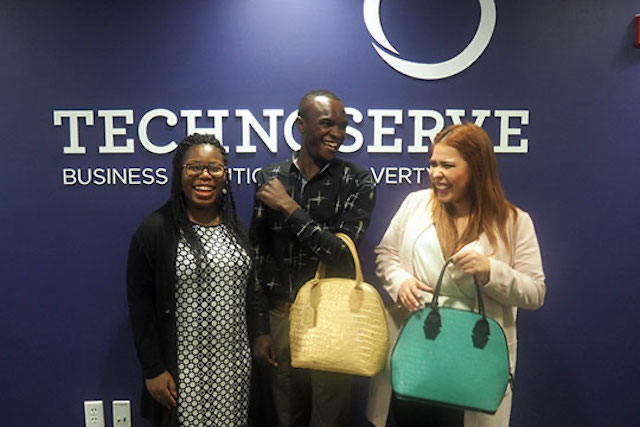 Young entrepreneurs try on handbags and pose for a photo