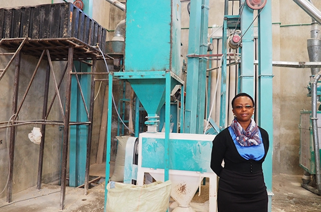 Pauline Kamau standing in-front of manufacturing equipment that she utilizes 