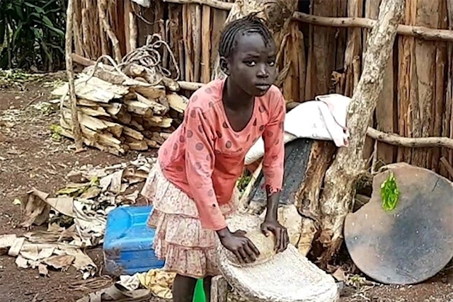Young girl grinding maize during her daily labor