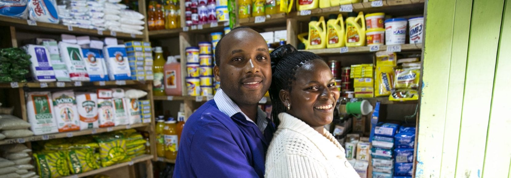 Smiling couple standing in their grocery store