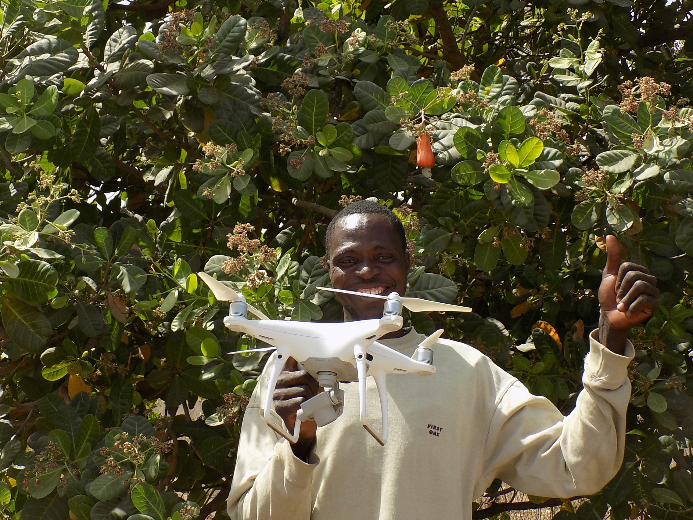 A man holds a drone in a field in Benin