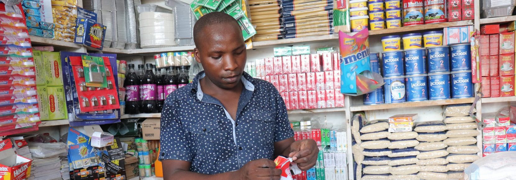 youth-owned shops open new doors for young people like Emanuel Barosha Ndiwene organizes products in his small shop in Dar es Salaam, Tanzania