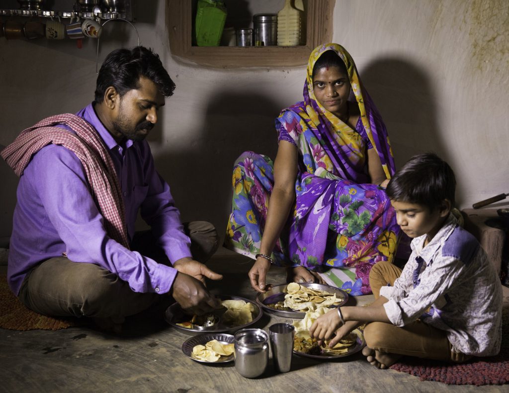 Family sitting on floor eating a meal - world hunger