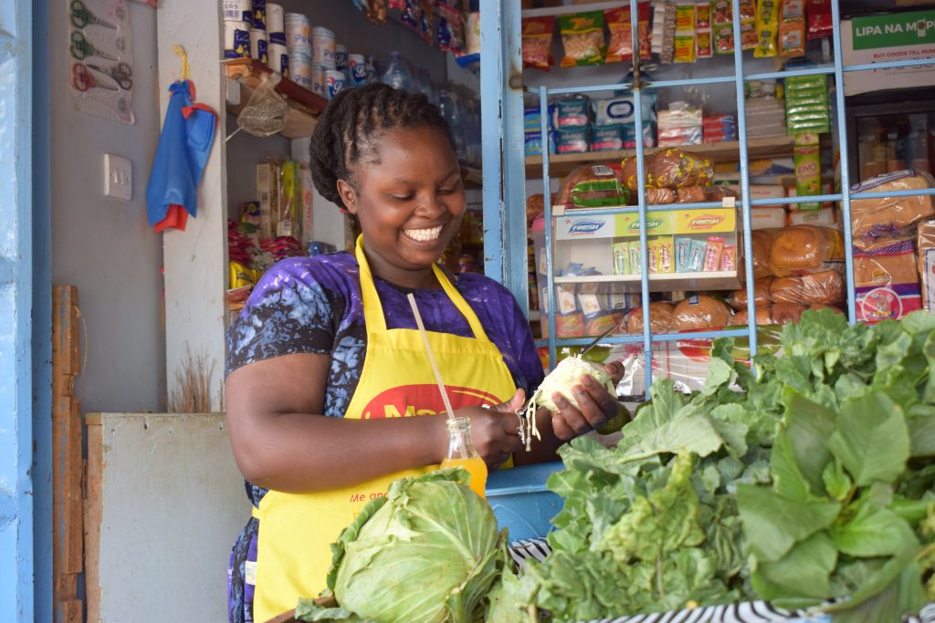 woman small business owner in Africa with produce smiling