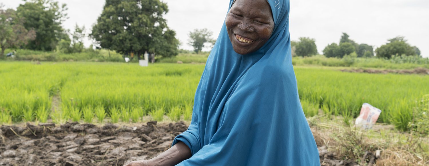 A farmer in Nigeria carries a handful of seeds on her plot of land.