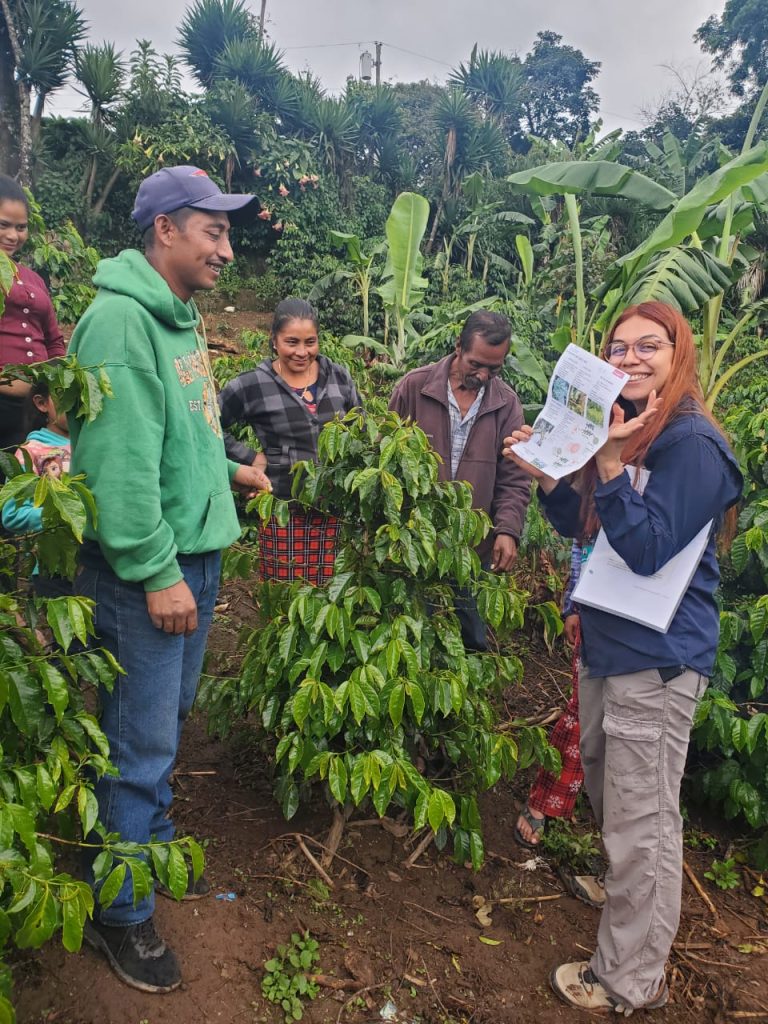 A TechnoServe farmer trainer in Guatemala stands with coffee producers—part of the 2023 TechnoServe staff reflections on being grateful. 