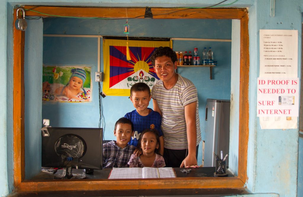 In this photo, a young man, Nyima Dhondup, is helping three young children connect to the internet in his cybercafe in Doeguling Tibetan Settlement in the Indian state of Karnataka. Dhondup won TechnoServe’s business plan competition as part of the Economic Development of Tibetan Settlements program. He used the prize money to buy computers, and TechnoServe’s advisors helped him launch and market his business in the community. 