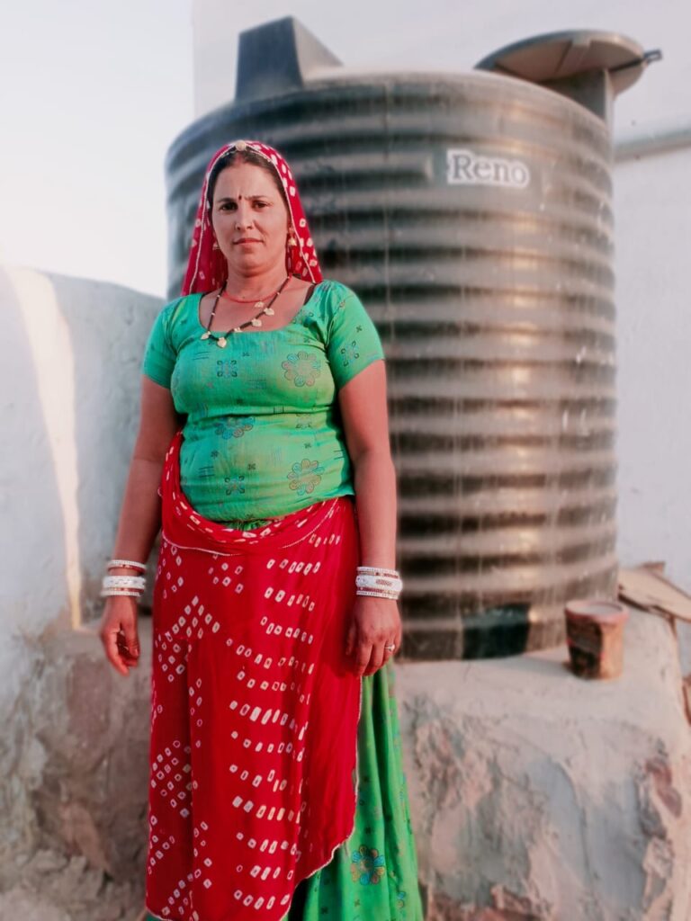 Manhori Devi standing in front of her rooftop rainwater harvesting system