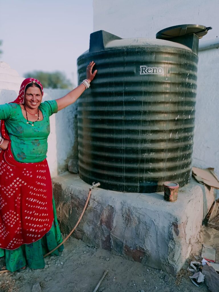 Manhori proudly shows the water tank that connects to her rooftop rainwater harvesting system and improves her family’s access to water. During periods of high temperatures and drought, this system ensures her family has a reliable water supply. (TechnoServe)